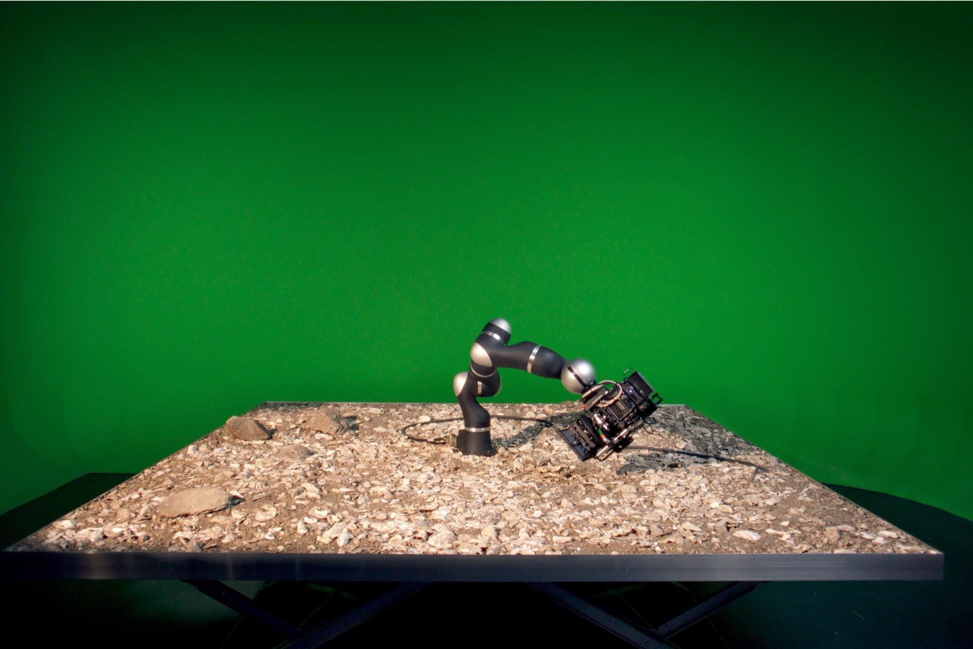 the camera is suspended by the robotic arm over rocks and gravel