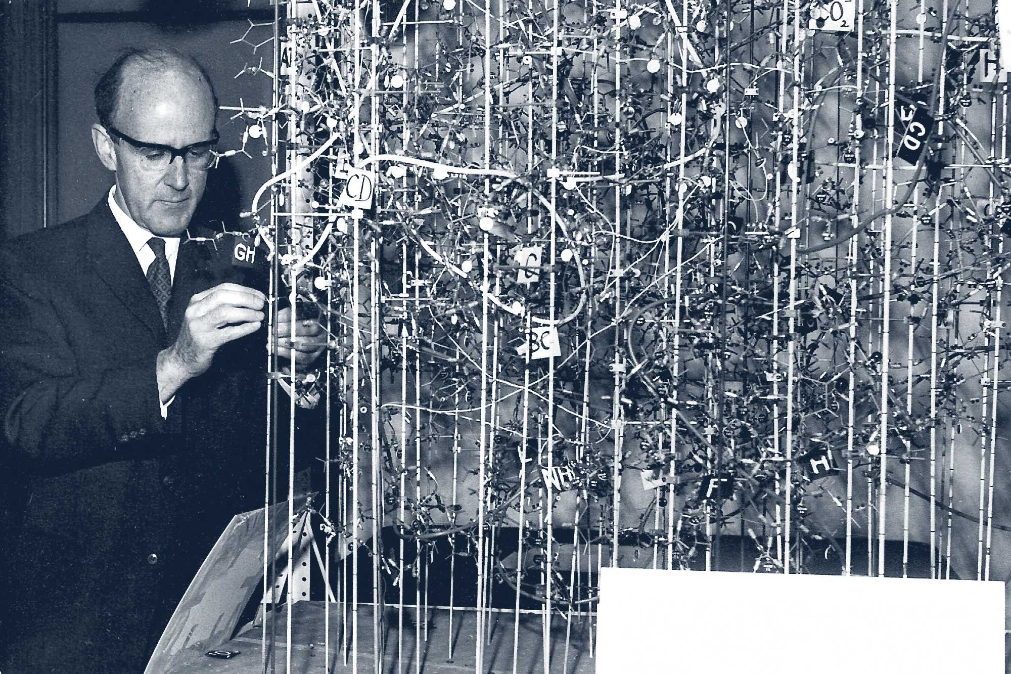 Wide view of Max Perutz working in his laboratory with molecular models