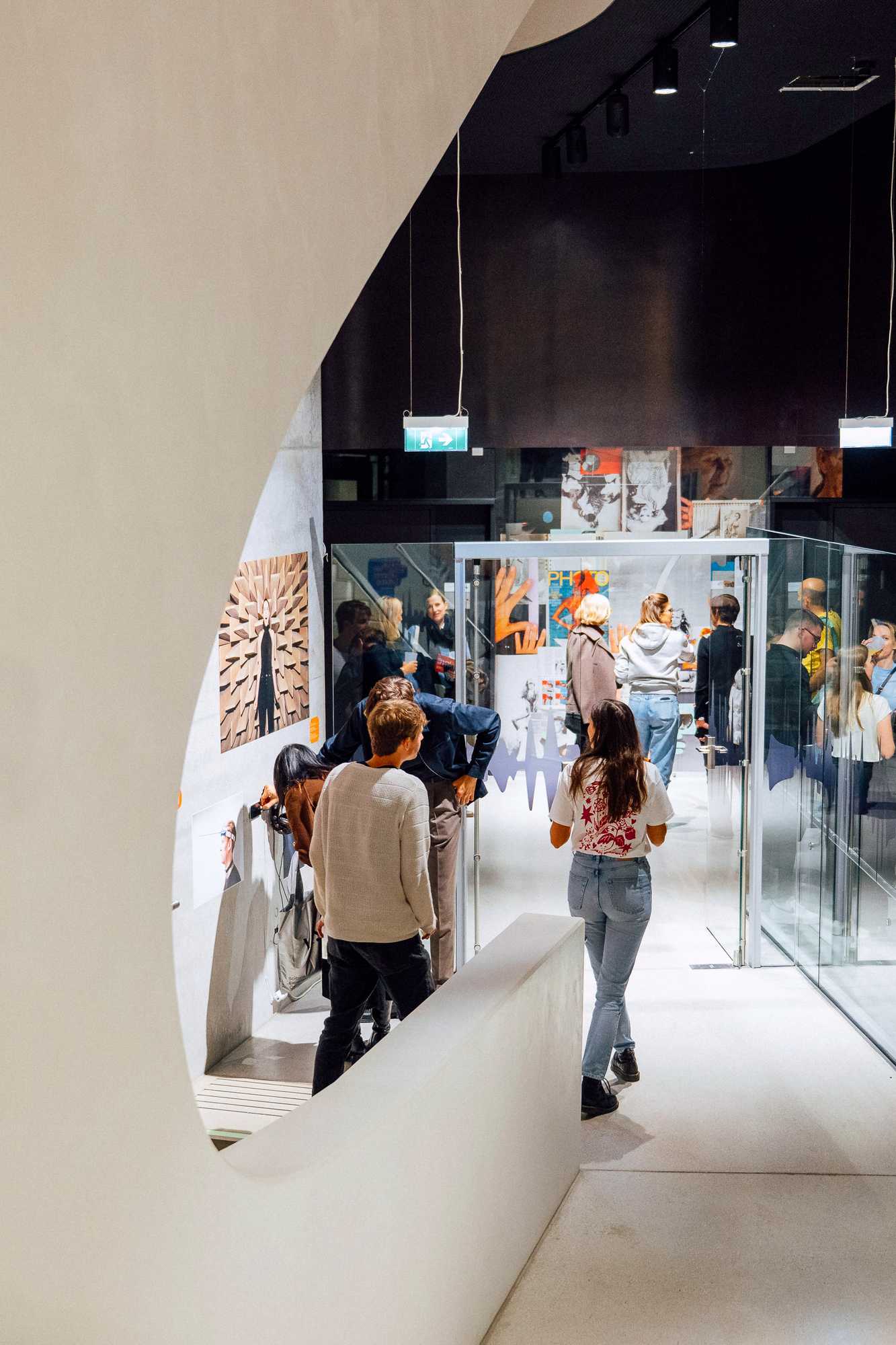 Besucher·innen versammeln sich in den geschwungenen Räumen der Ausstellung