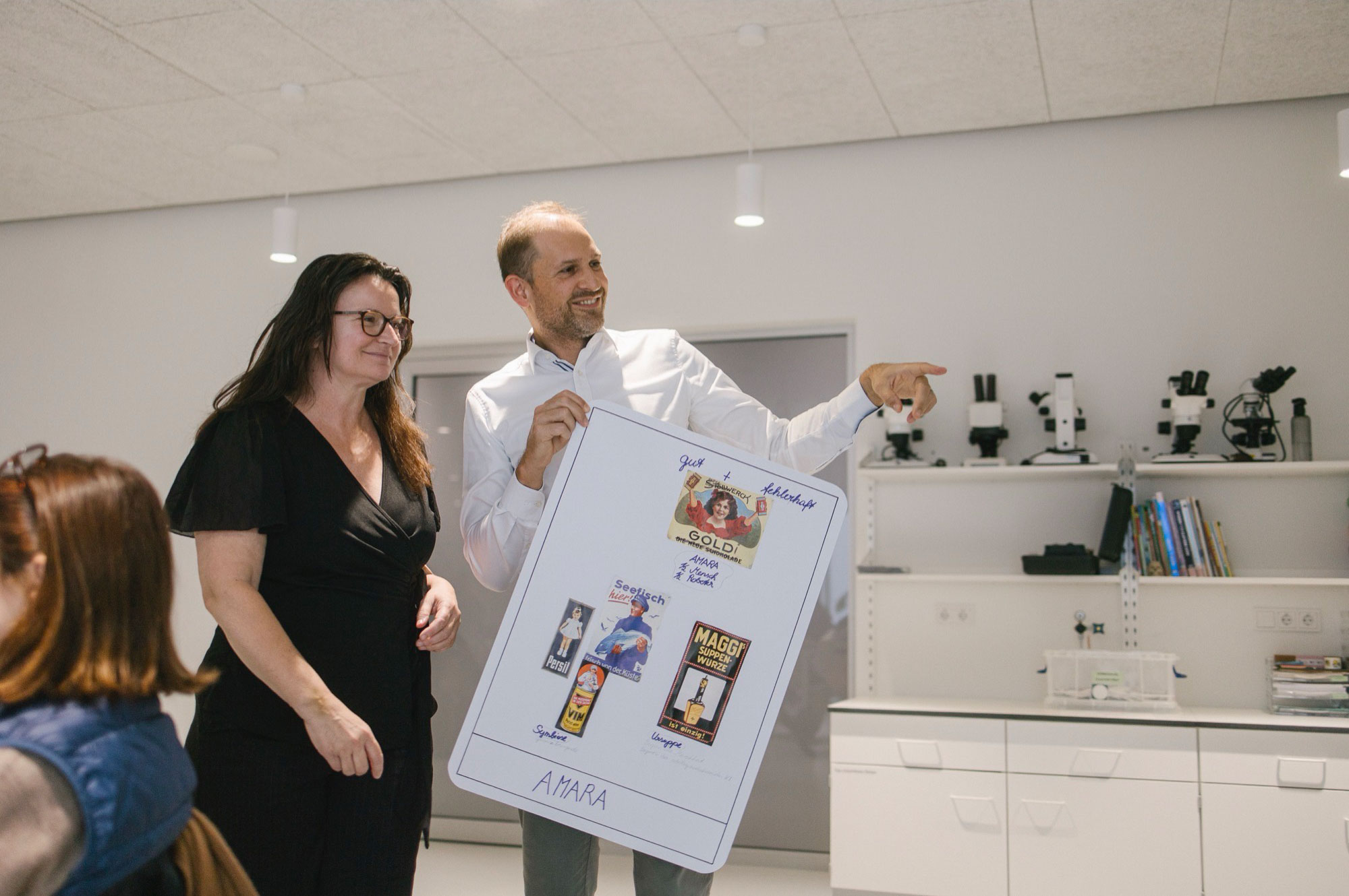 Photograph of two workshop participants holding their tarot-card-poster.